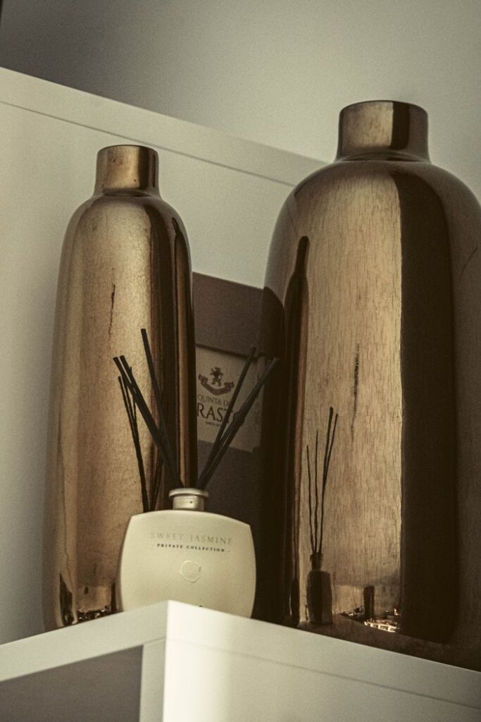 Sophisticated arrangement of metallic vases and sweet jasmine diffuser on a shelf.