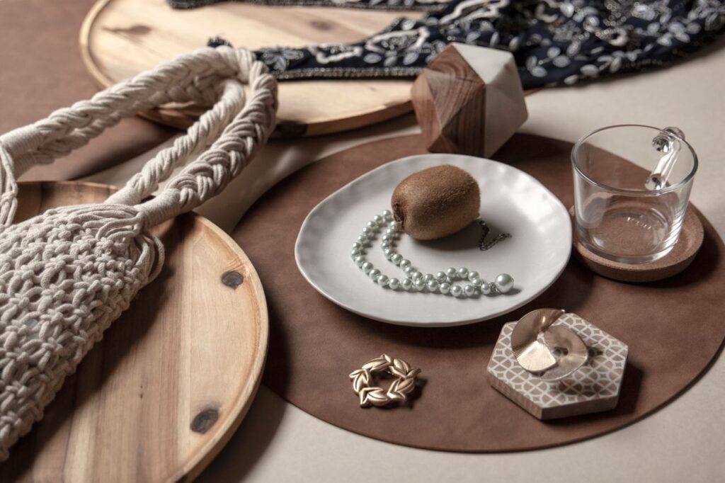 A sophisticated still life featuring a kiwi, pearls, and decorative accessories on a wooden surface.